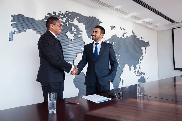 Businessmen shaking hands in front of a world map Businessmen shaking hands in front of a world map