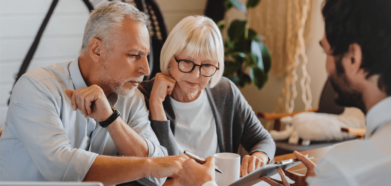 Agent explaining paperwork to elderly retired couple front of desk