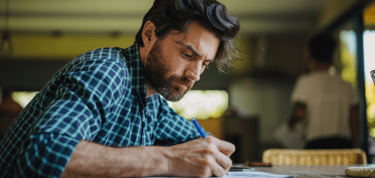 Mature white man with brown hair writing on a piece of paper