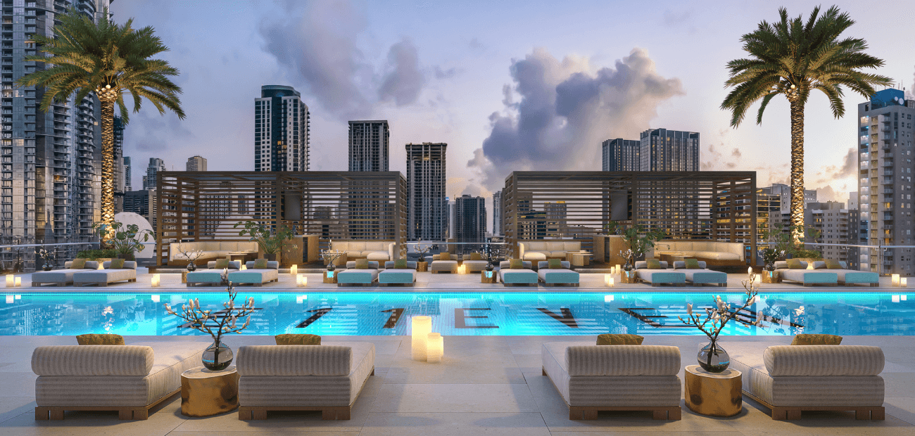 Photo of a rooftop pool flanked by palm trees with a city view