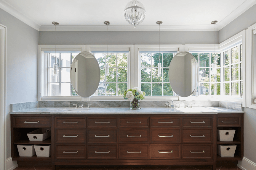 Photo of large, dual sink bathroom vanity with dark-wood drawers and oval mirrors