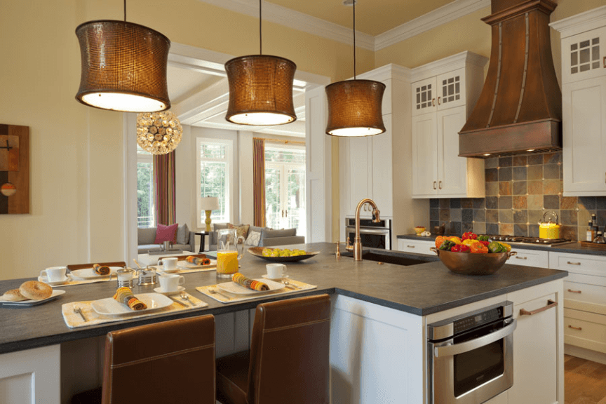 Traditional style kitchen with dark countertops and white, shaker cabinets. Also includes a copper hood vent and matching lights