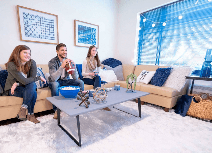 3 people sitting at couches in a living room, with a white carpet. 