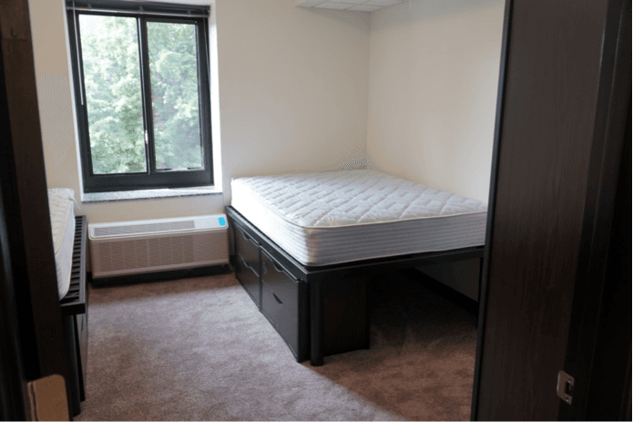 A bare dorm bedroom with stripped mattresses.