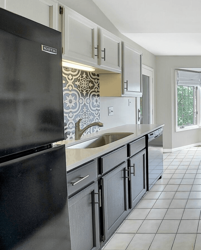 A kitchen counter with sink, showing a decorative back splash