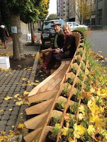 People sitting on a bench in a quiet street located in a greenway neighborhood in Portland, OR