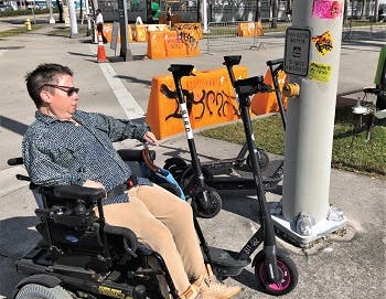 Woman in wheelchair next to parked scooters