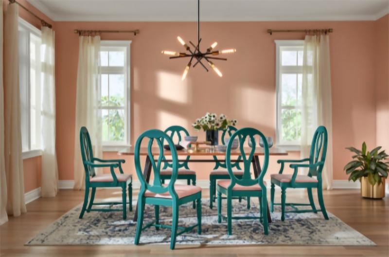 A Rose "Blush" color painted dining room with teal-green chairs around a table.