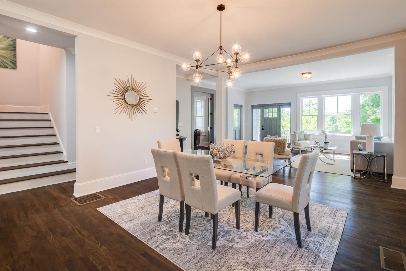 An all white dining room brightened by the use of warm colored chandelier bulbs