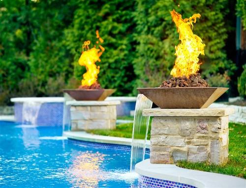 A contemporary pool with waterfalls and gas lighting features