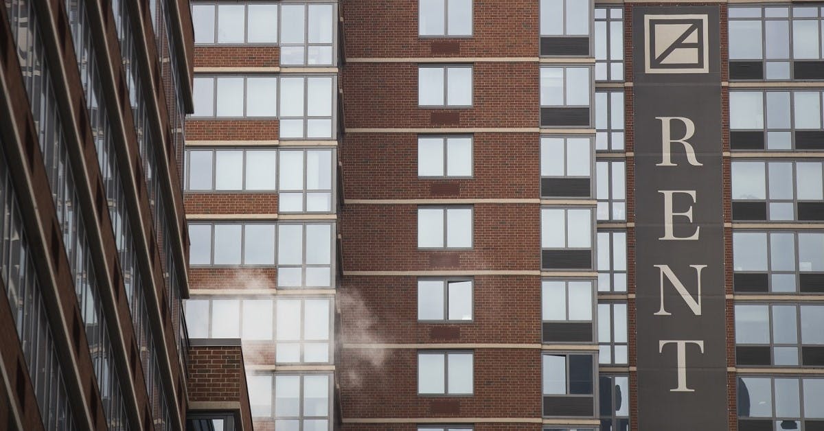 A shot of a highrise apartment building with a large rent sign