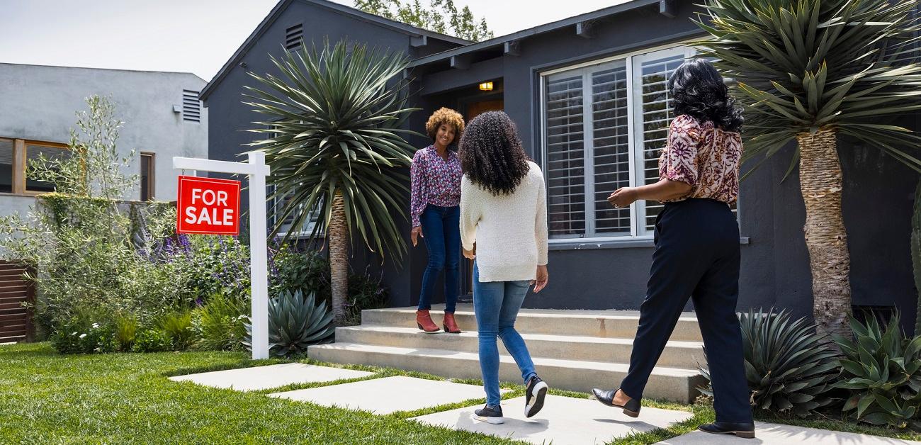 saleswoman greeting female customers while standing outside house