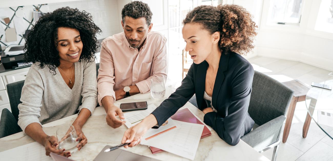 Real estate agent and two clients looking at computer at a table