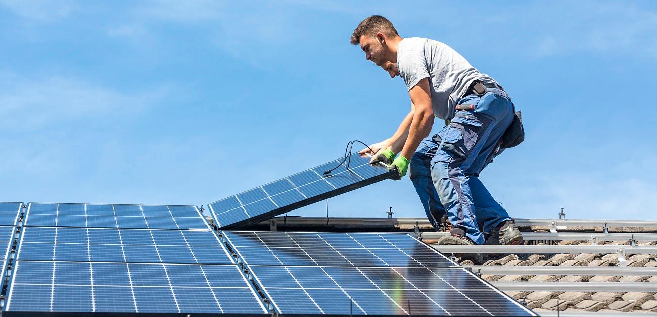 Workers installing solar panels on roof