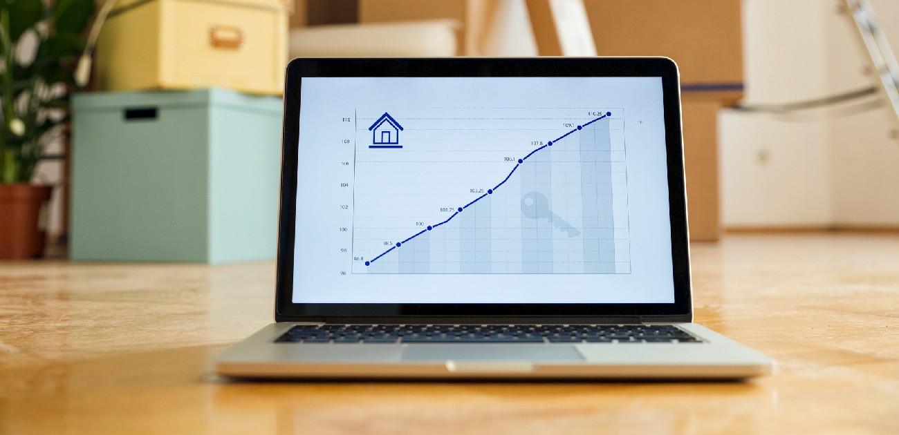 A picture of a laptop's screen showing a line graph that charts the increase in home prices over time.