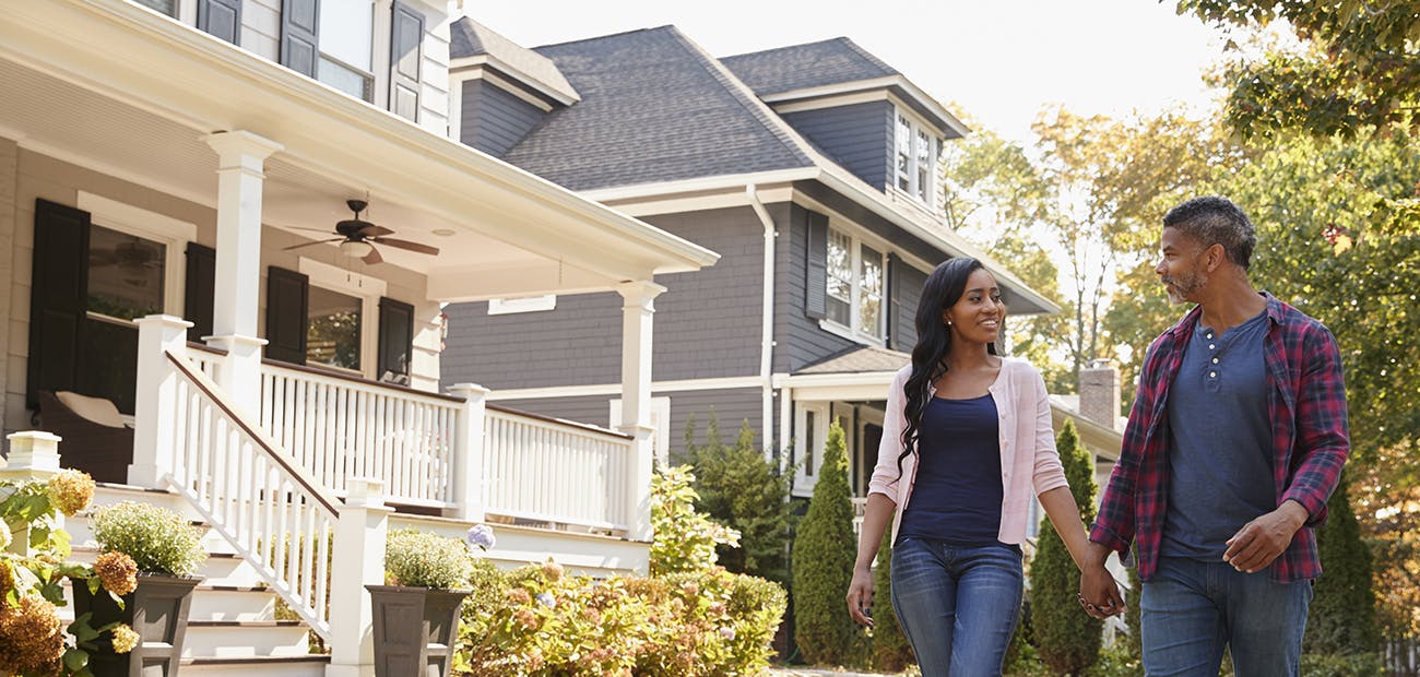 Couple Walking Along Suburban Street Holding Hands