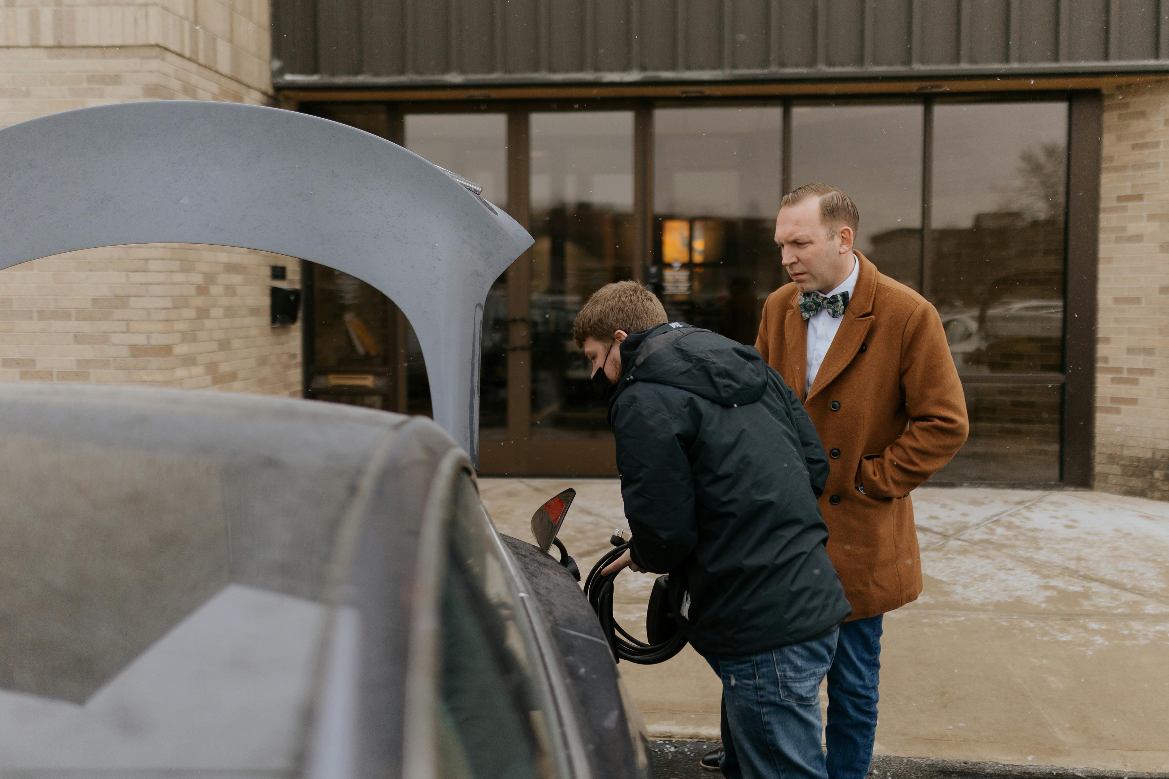 Two men charging an electric car.