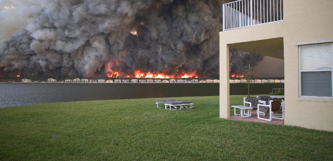 A picture of a wildfire from a distance, with large billows of smoke filling the sky.