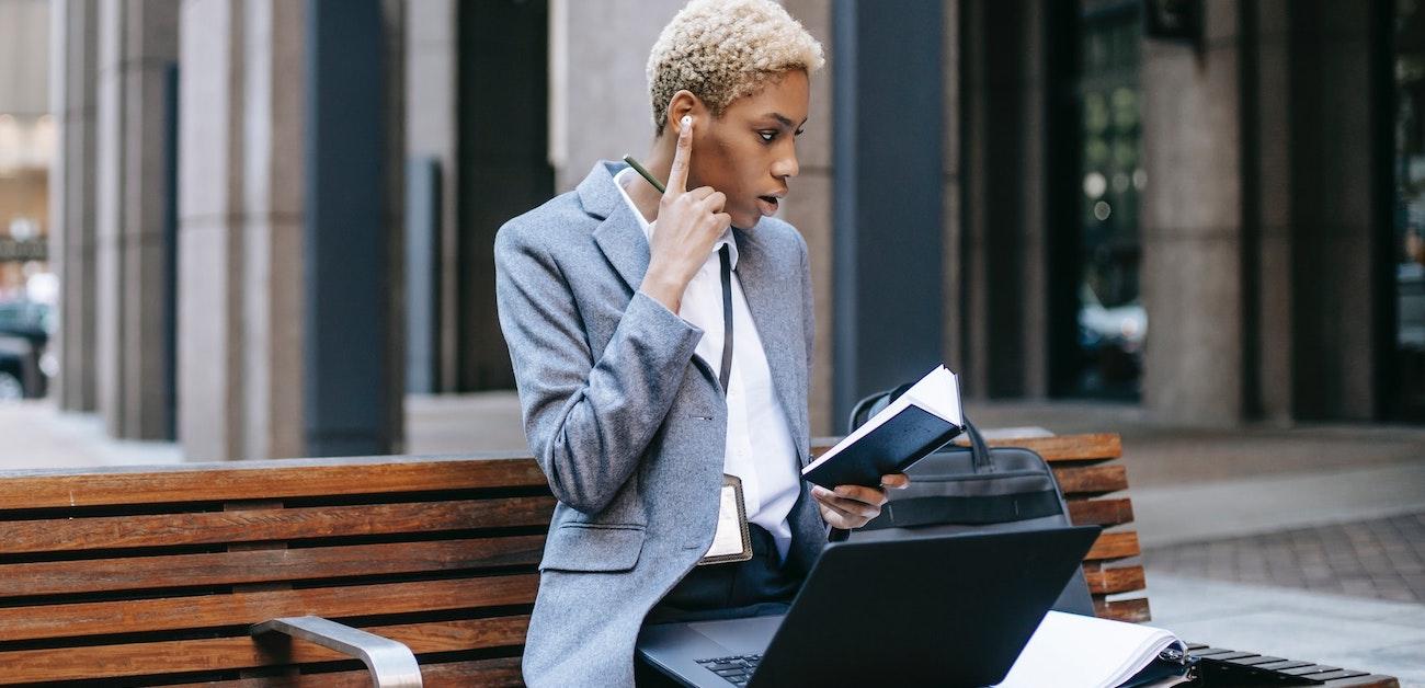 Woman sitting on bench talking on phone while on computer