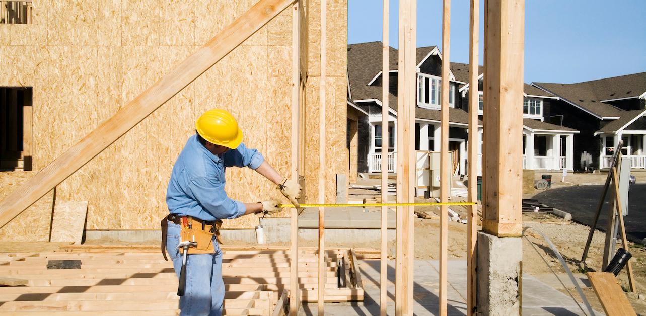 Construction worker measuring at new home site.