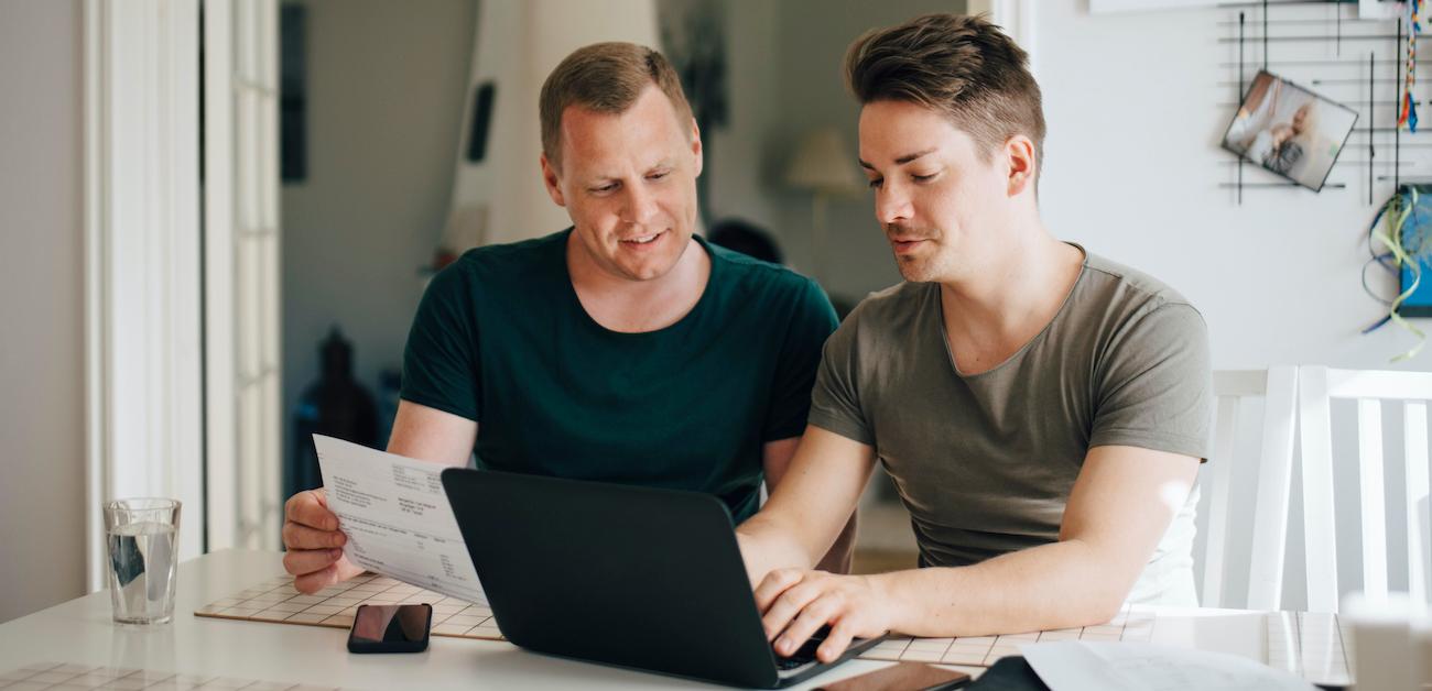 Gay couple completing home closing or financial transaction on laptop computer.