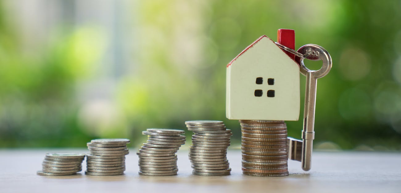 House on top of stacks of coins on table.