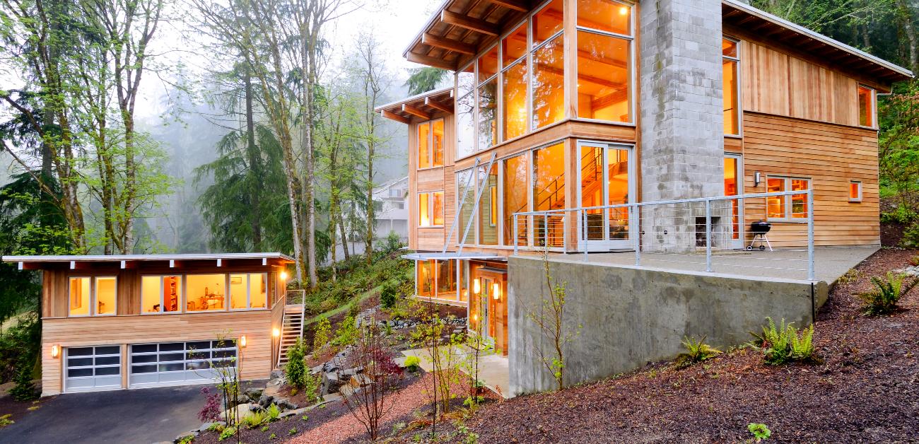 A house in a woodland area elevated upon a hill on the right, with an ADU and garage to the bottom left.