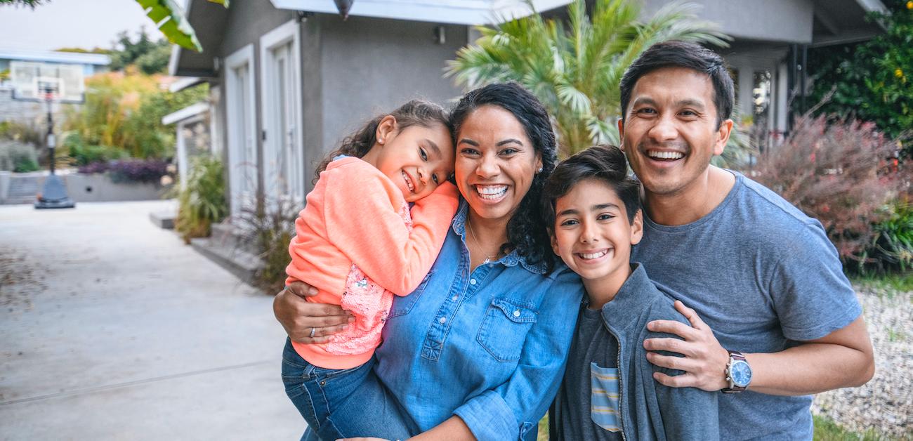 Multi-ethnic parents and children are smiling on driveway. 