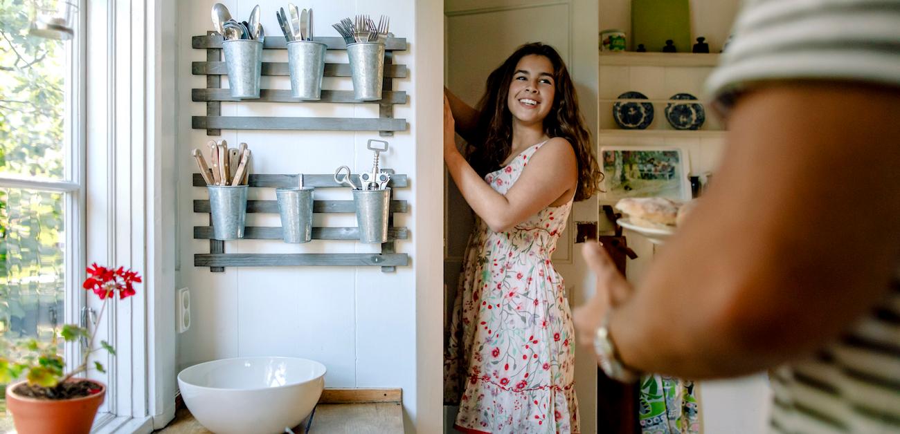 Smiling daughter talking to father while standing by kitchen pantry.