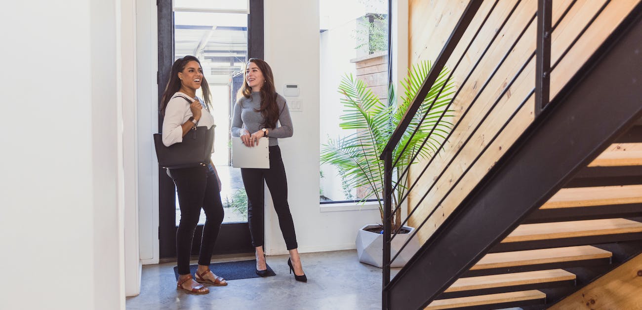 Woman enters new home with real estate agent.