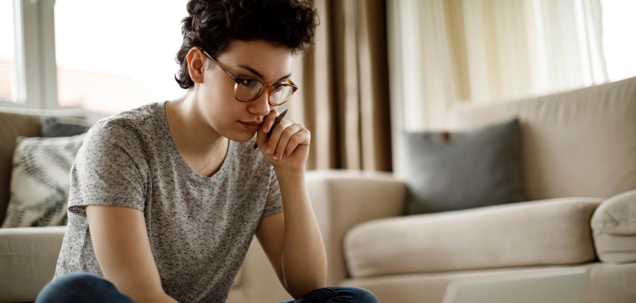 A woman staring thoughtfully at her laptop computer