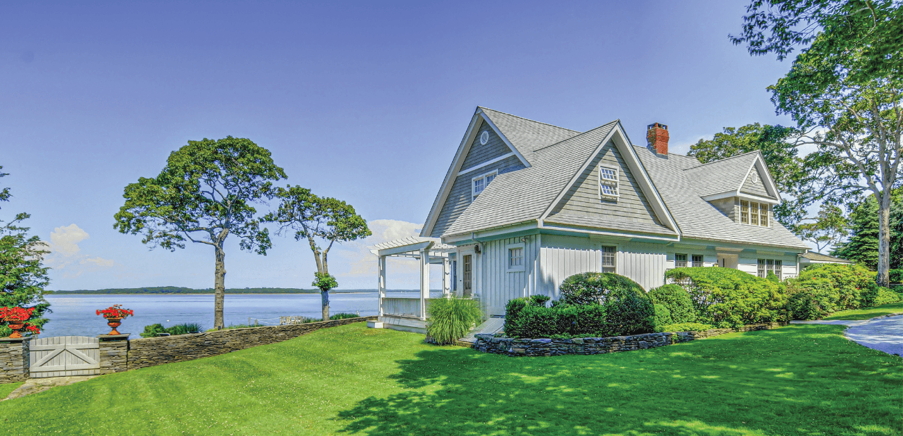 A muted tone home with peaked roof overlooking a lake