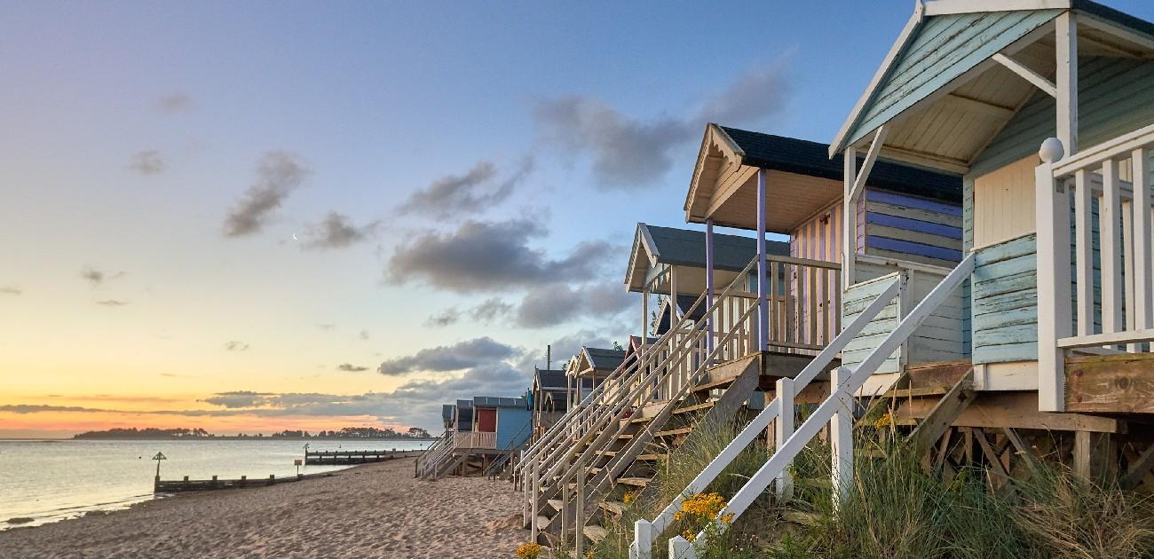 A picture of a row of beach houses along a coastline of a sea.