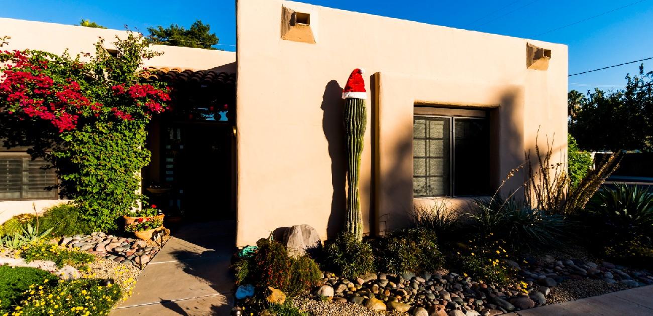 A picture of a southwestern style home, with plants and decorative stones in the small front yard.