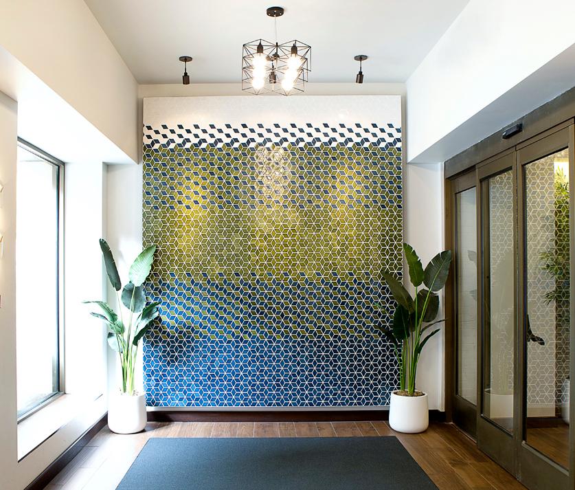 A gradient tile art piece of geometric patterns composed of sage greens and blues adds texture to the space.