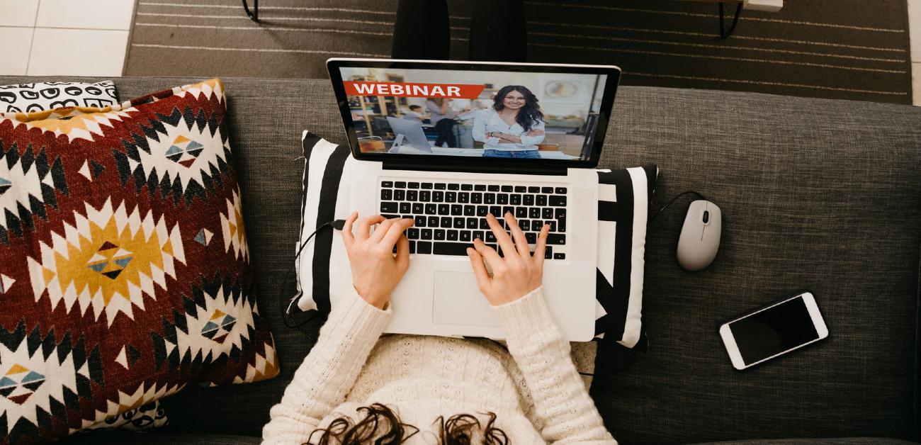 A picture from directly above a woman on a sofa using her laptop to watch a video.