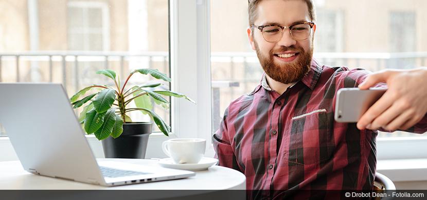 Man taking selfie in front of laptop computer.