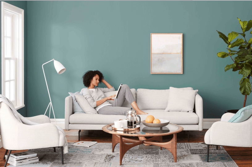 a woman sitting in a living room with a teal wall