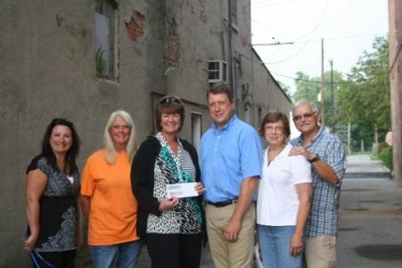 MIBOR President Kathy Hall presents the grant check to members of the Fortville Action, Inc. in the alley.