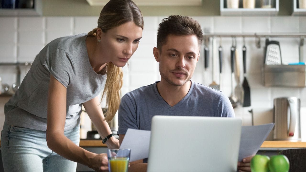 Couple viewing computer screen and paperwork