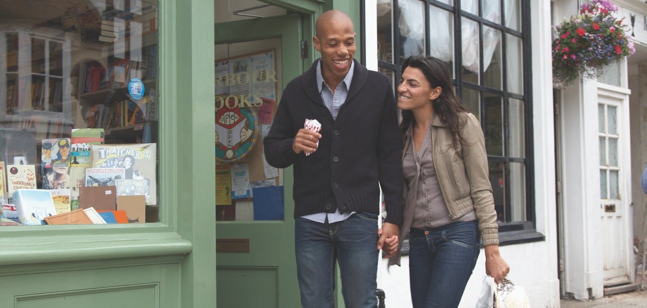 Couple walking along shopping district street