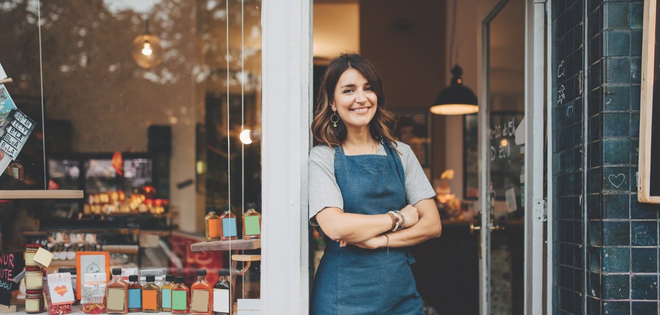 Smiling shopkeeper in doorway of a retail business.