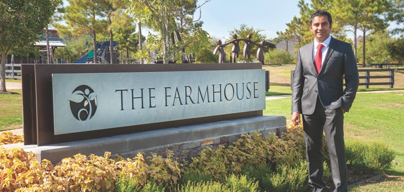 Imran Bhaidani standing by The Farmhouse sign at Harvest Green