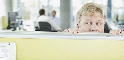 Man peeking over cubicle