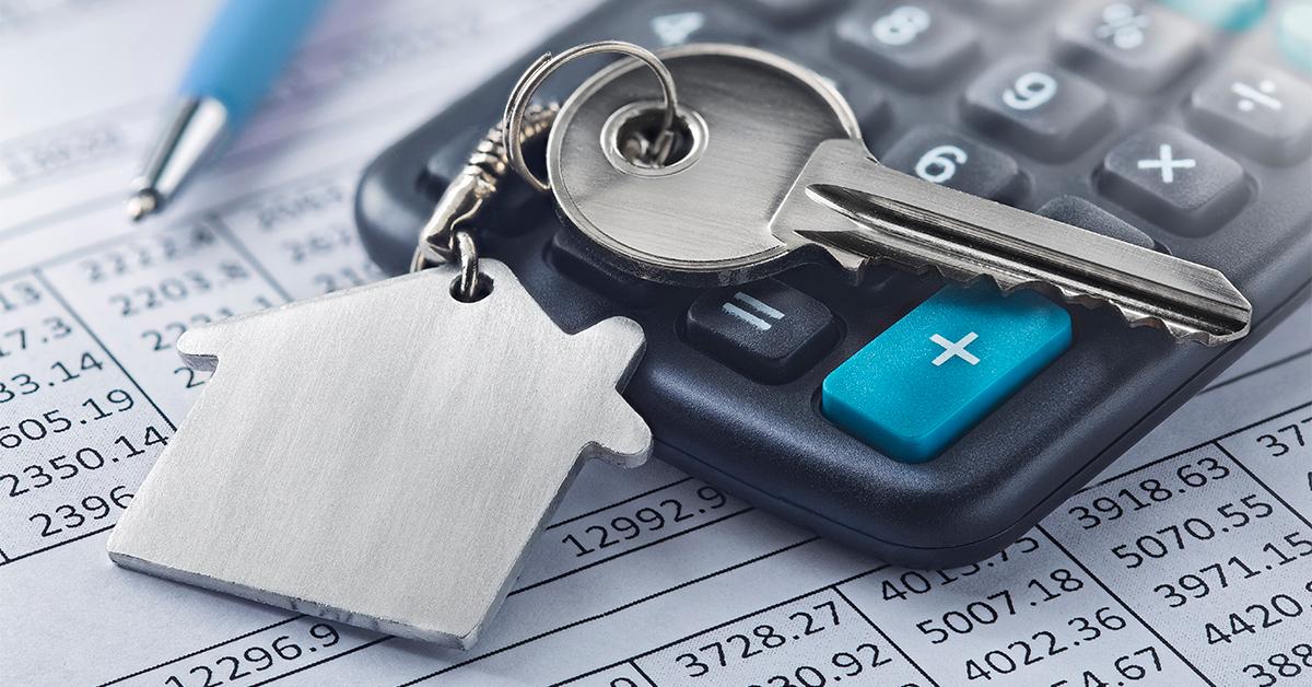 Financial papers, calculator, key on house keychain