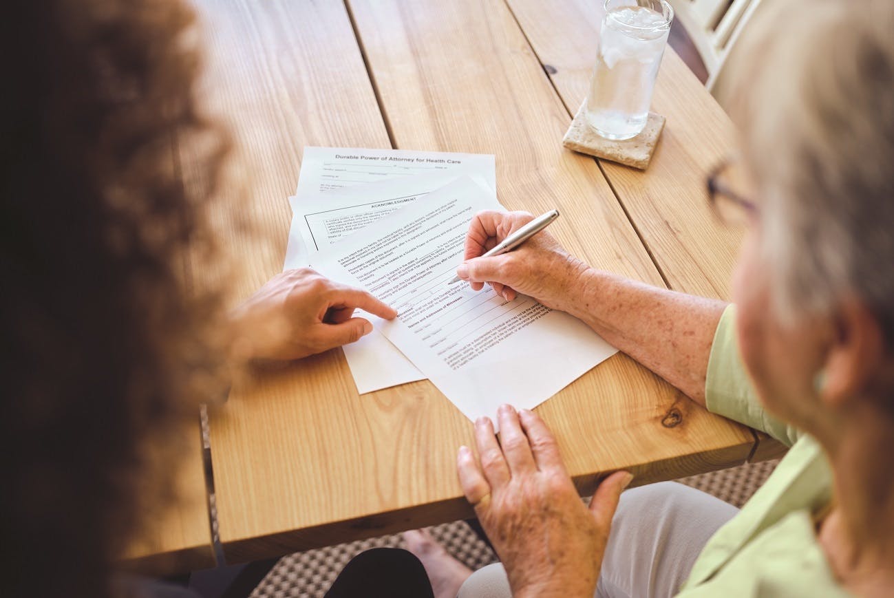 High Angle View from Behind of a Real Estate Agent Assisting a Client with the Process of Signing a Contract