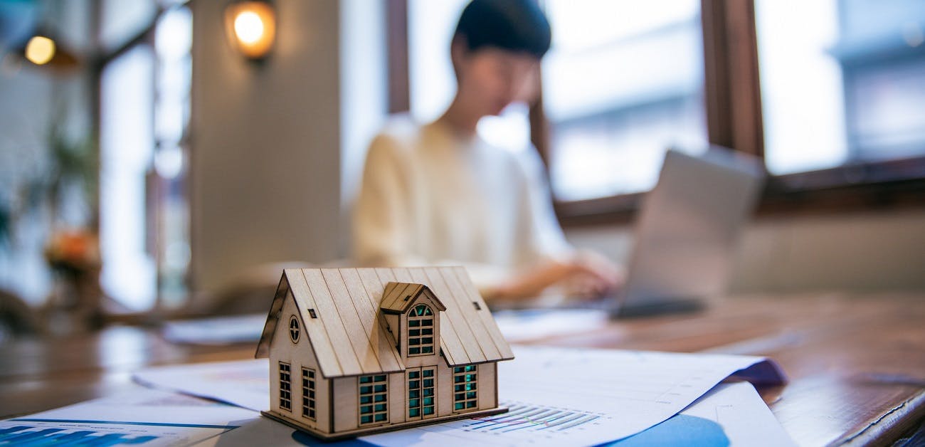 home model in foreground and real estate agent working on computer in background