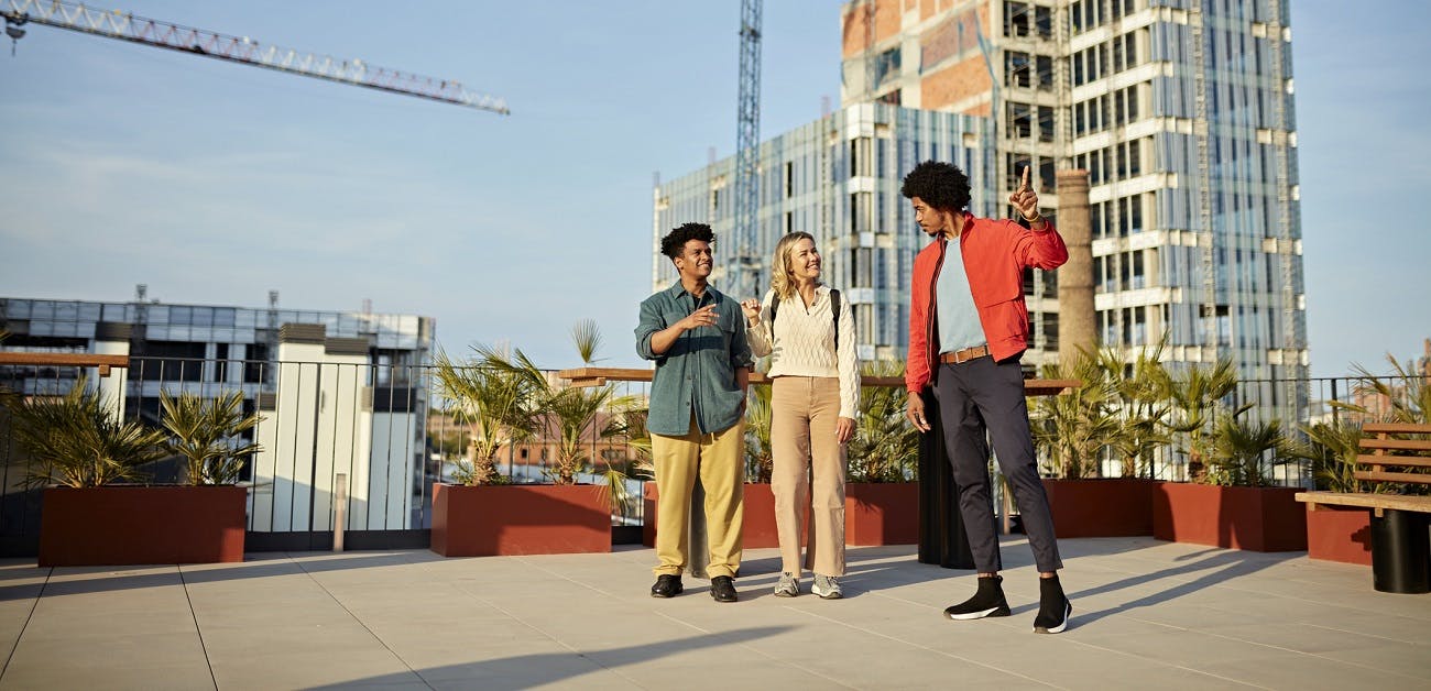 People on rooftop with cranes in background