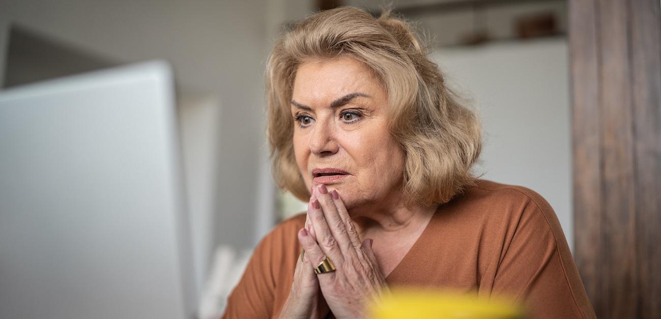 Woman looking shocked while using a laptop at home