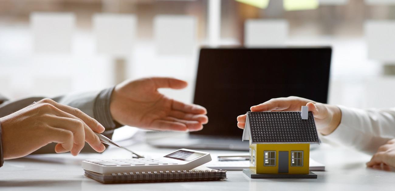 People talking at table with calculator and house model